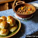 현지 음식을 통해 배우는 문화 - A rustic Polish kitchen scene showcasing a wooden table laden with traditional dishes such as żurek ...
